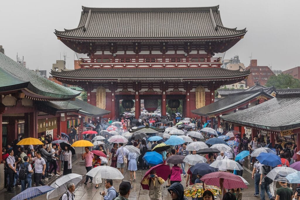 Visitors with umbrellas beneath the Hōzōmon gate of Sensō-ji temple in Asakusa on a rainy day