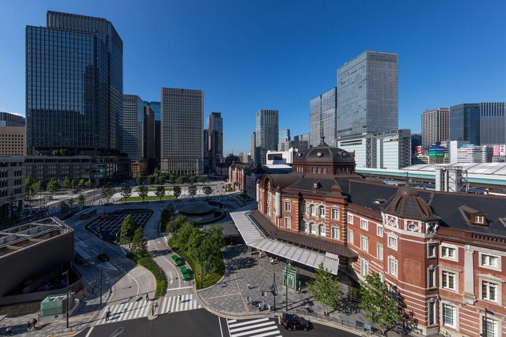 Tokyo Station's red-brick Marunouchi building and the plaza in front of it, seen from above on a clear afternoon