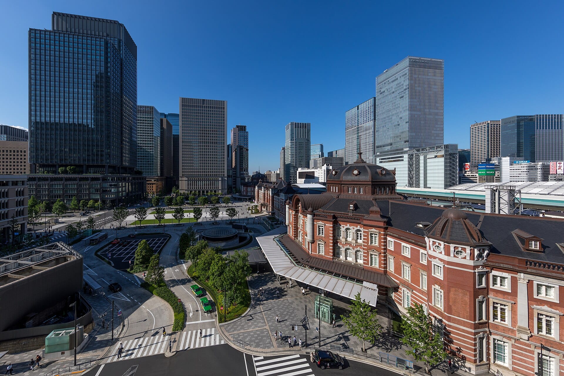 Tokyo Station's red-brick Marunouchi building and the plaza in front of it, seen from above on a clear afternoon
